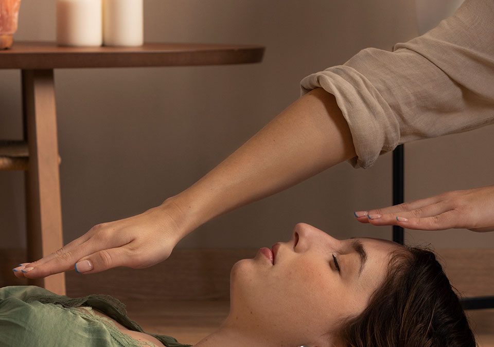 Mujer tumbada en el suelo y otra persona poniendo una mano sobre su cabeza y otra sobre su pecho