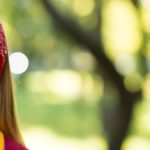 Primer plano de una chica sonriendo. Fondo difuminado de bosque o parque.